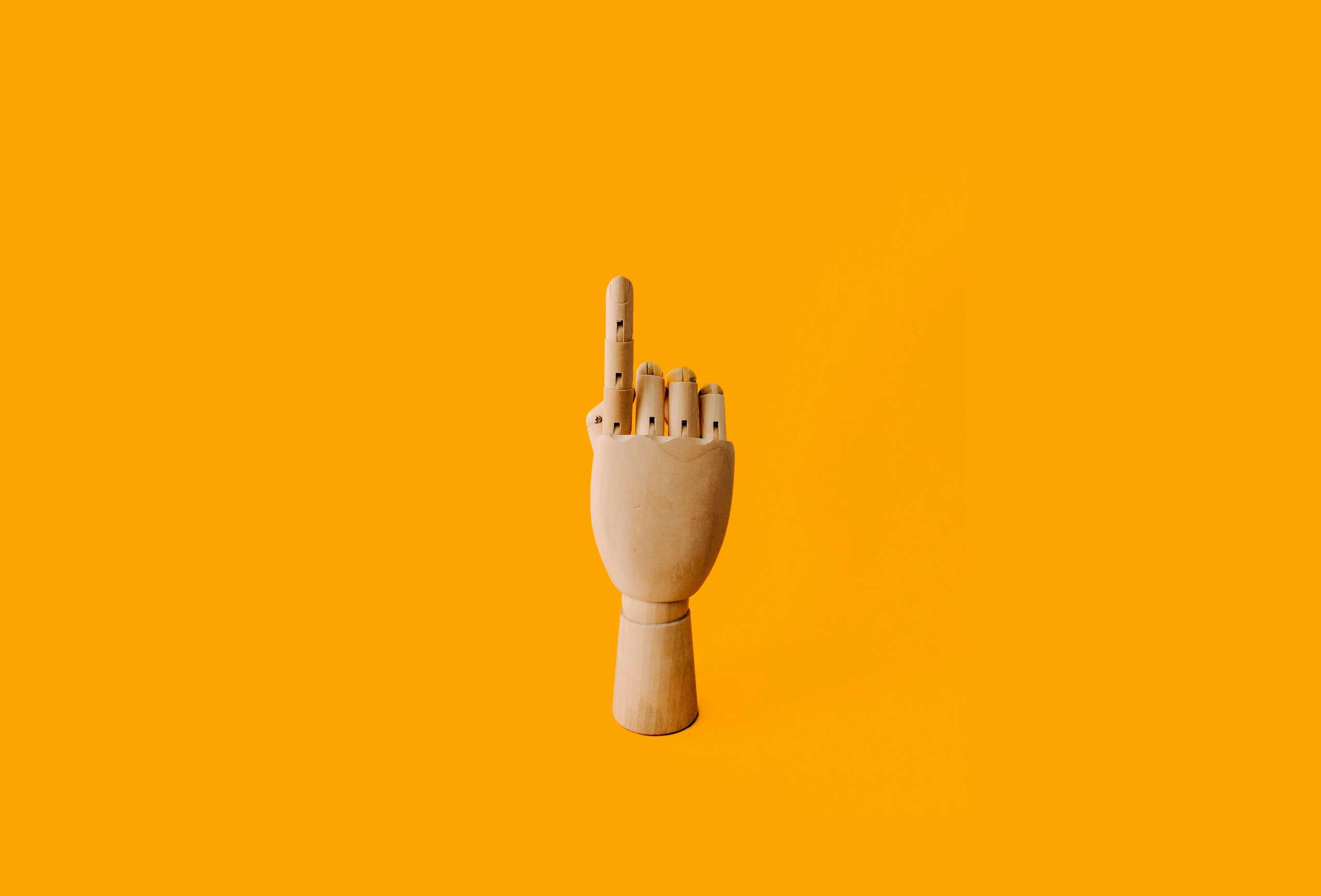 PointingUpwardCharlesDeluvioFeb2018 Beige Wooden Hand with Index Finger Pointing Upward Against Orange Background
